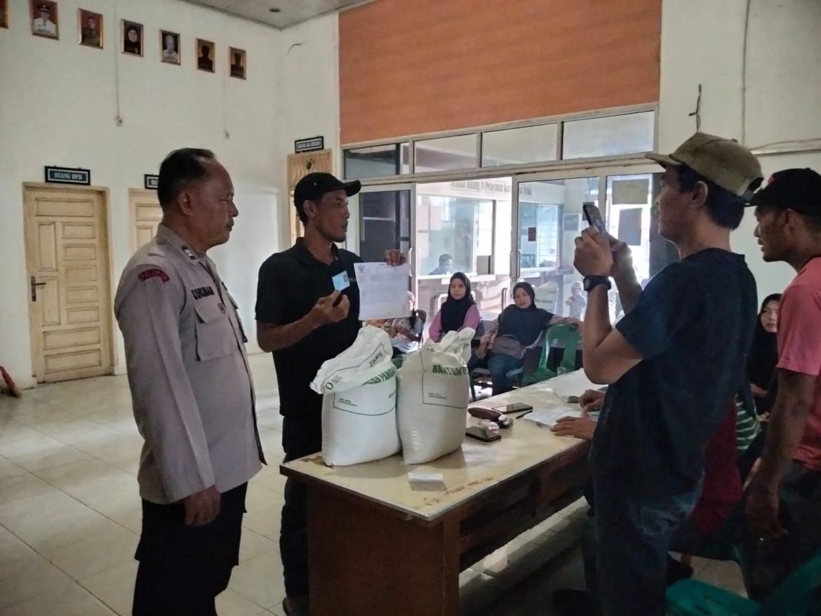 Bhabinkamtibmas Desa Teluk Monitoring Pembagian Beras Bulog di Kantor Desa.